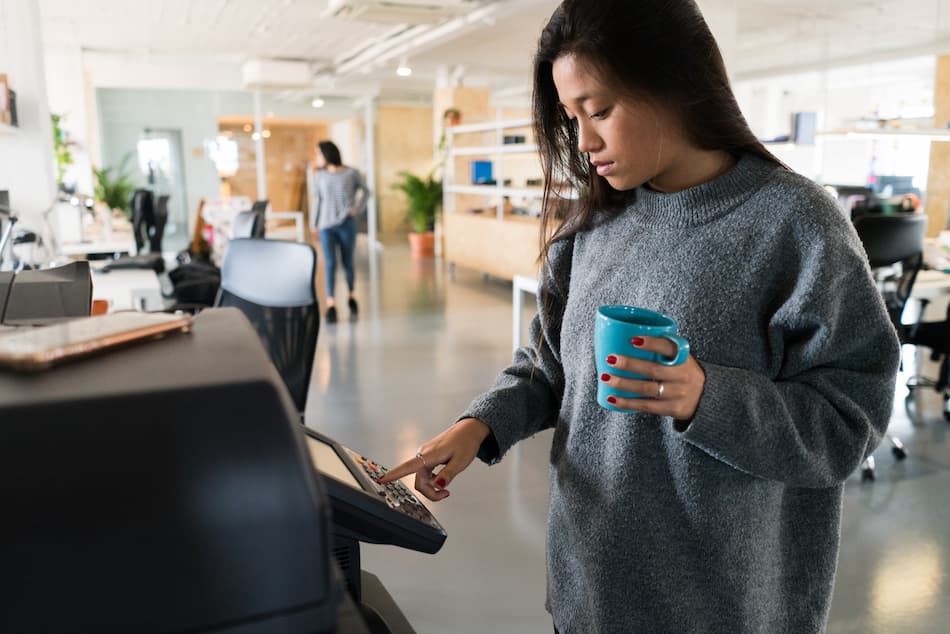 black woman with coffee using a commercial printer