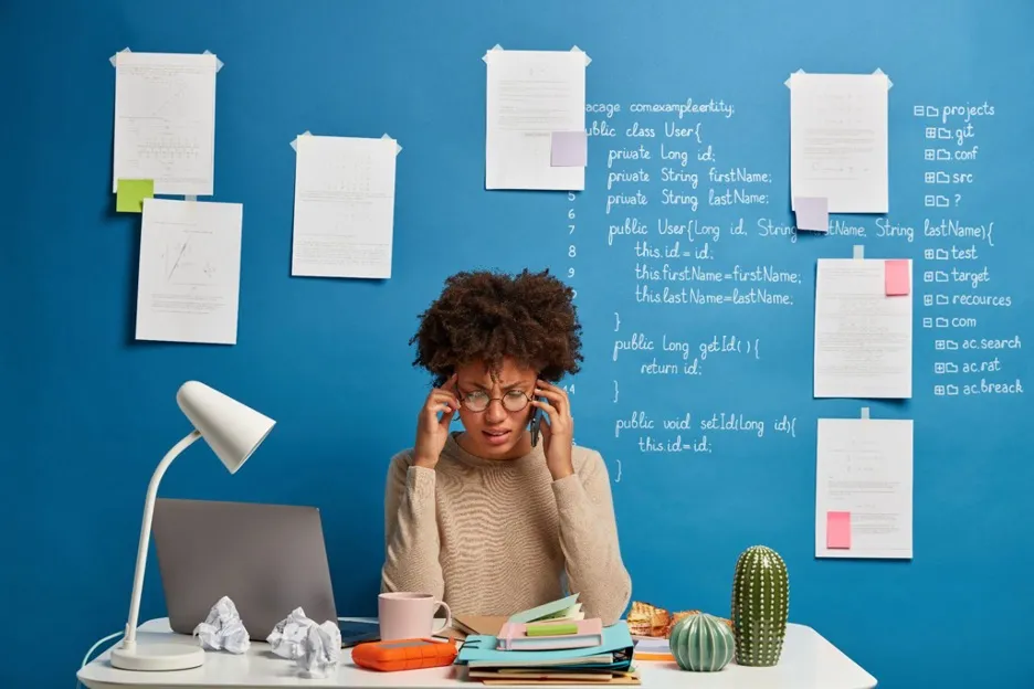 10 Common Writing Errors AI Can Help You Avoid: Tips for All Skill Levels 9 A stressed woman at her desk, talking on the phone, visibly upset after a written mistake caused by AI.