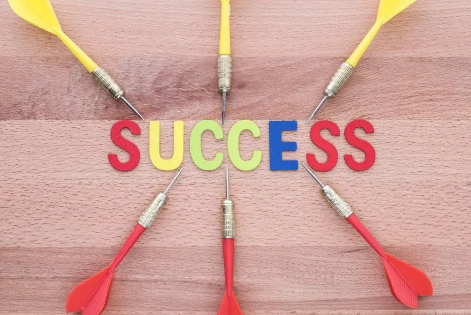 a group of darts on a table pointing to the word success